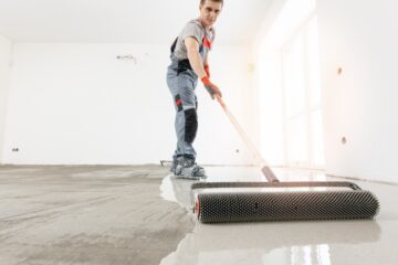 Master with needle roller for new screed concrete with mixture of cement for leveling for floors. Concept building renovation home
