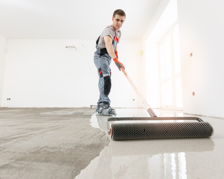 Master with needle roller for new screed concrete with mixture of cement for leveling for floors. Concept building renovation home