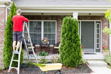 A homeowner in the front patio area completing a few often overlooked home maintenance tasks.