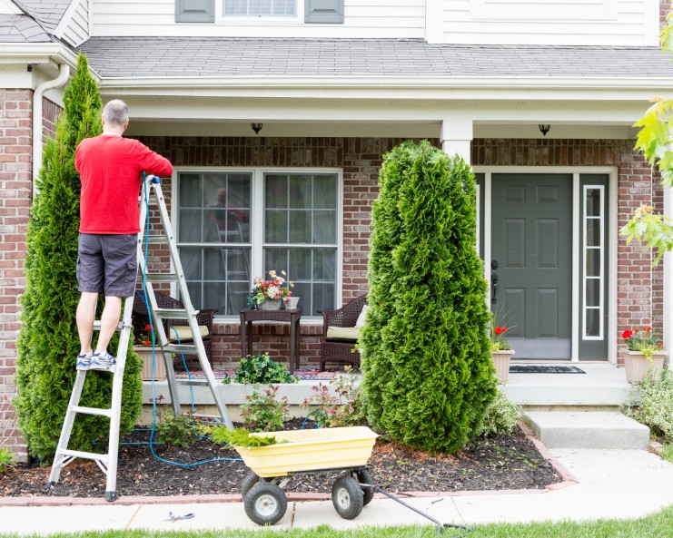 A homeowner in the front patio area completing a few often overlooked home maintenance tasks.