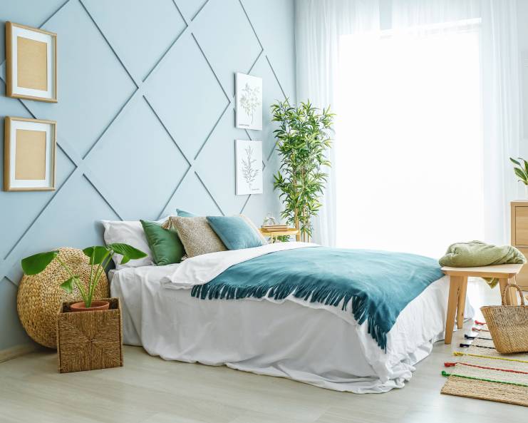 A modern, boho bedroom design with a splash of teal and wood elements for a natural look. There's a lot of natural light.