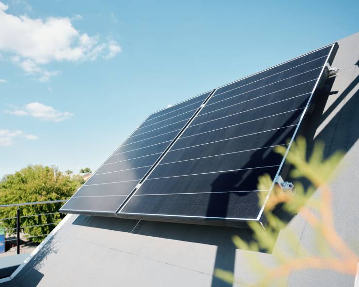 Two large solar panels installed on a roof. There is a wooden planter near the solar panels on the roof.