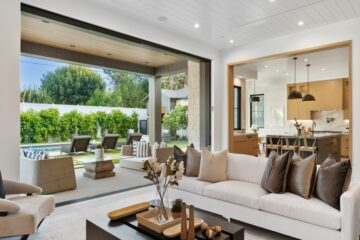 A living room with modern decor has an open floor concept that connects the kitchen and the outdoor space.