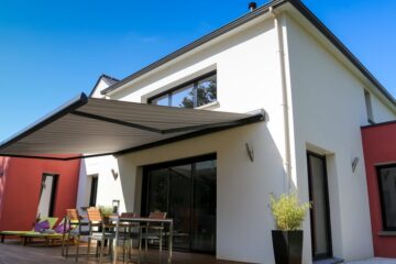 A beautiful white home with a back patio area off the sliding glass door. There's a retractable awning over the patio.