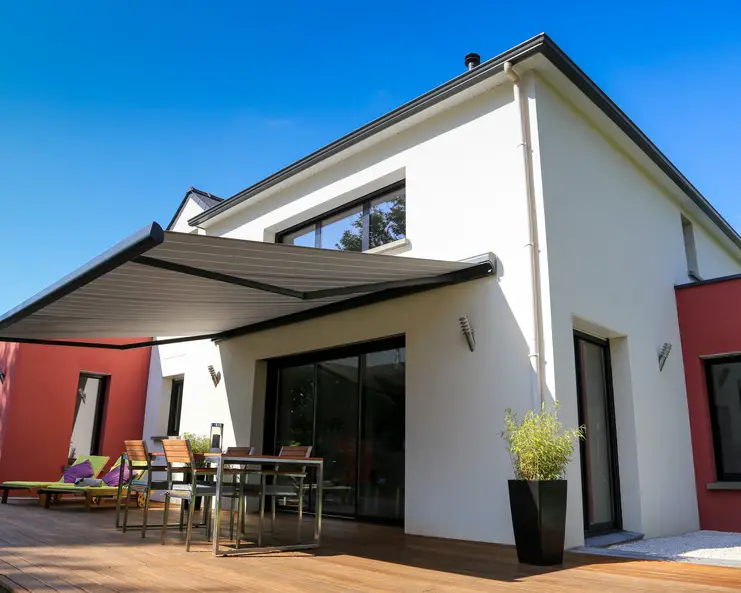 A beautiful white home with a back patio area off the sliding glass door. There's a retractable awning over the patio.
