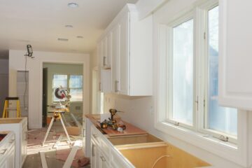 An empty, bright white kitchen undergoes renovations that include new countertops and electrical wiring.