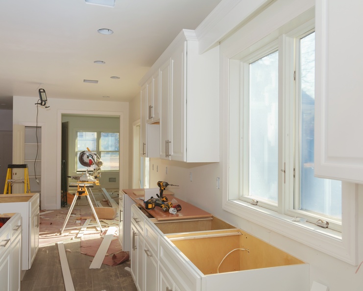 An empty, bright white kitchen undergoes renovations that include new countertops and electrical wiring.