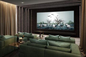 A dark home theater with a large screen, four two-seat couches, two small tables with drinks, and curtains on the walls.