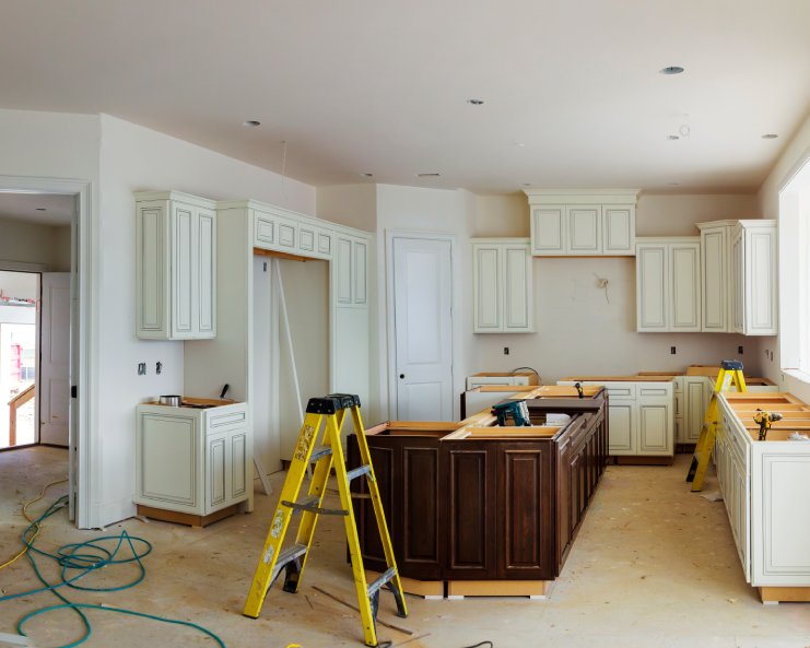 A kitchen is getting remodeled with new countertops. There's a ladder next to the island.
